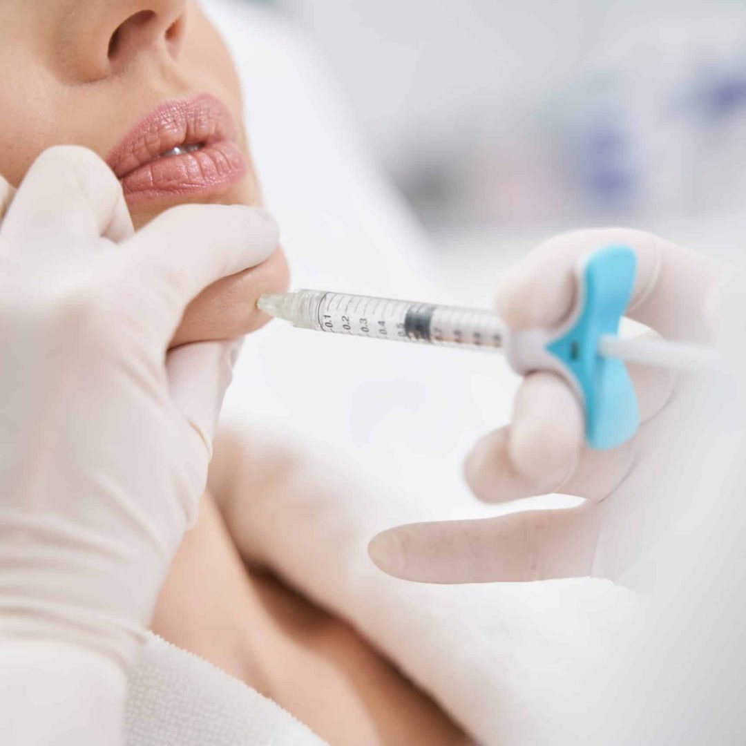 Doctor cosmetologist making beauty injection into woman chin Close up of female client receiving face lifting contour plastic injection in cosmetology clinic