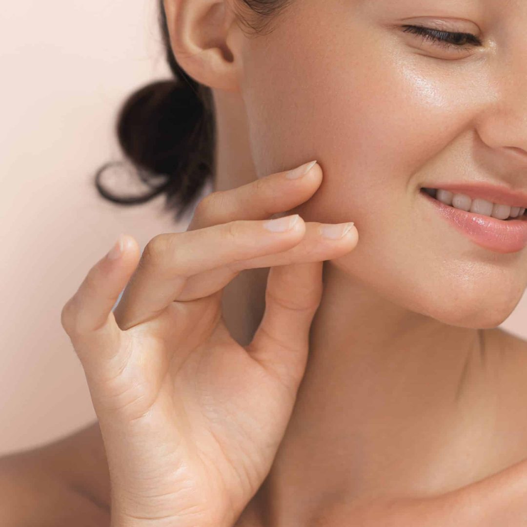 Cosmetics Skin Care Concept Photo of Close-up Woman Perfect Face with Hydrated Skin High-quality photo of skincare and cosmetics concept. Woman with beautiful face touching healthy facial skin portrait. Beautiful happy Asian girl model with natural makeup enjoys glowing hydrated skin